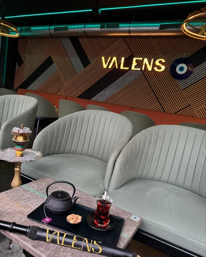 Lounge-Ecke im Valens mit grünem Samtsofa, Tee-Set und Leuchtschrift
